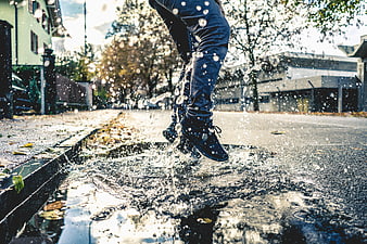 Man jumping in puddle on wet street with water splashes
