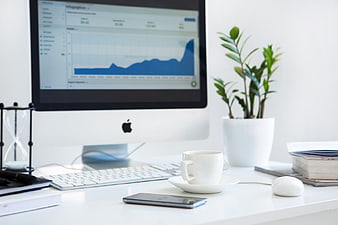 Minimalist white office desk with computer charts and coffee