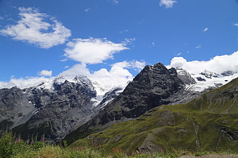 Majestic Snow-Capped Alps with Green Meadows and Blue Sky