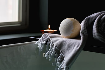 Bath Bomb and Candle on Bathtub Edge with Towel