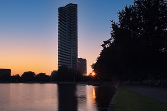 Tall Skyscraper Silhouette at Sunset Over Lake