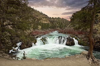 Scenic waterfall in a forested canyon at dusk