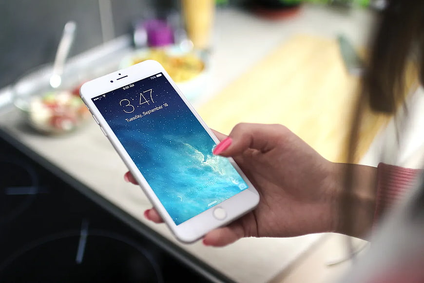 Woman holding white smartphone in modern kitchen