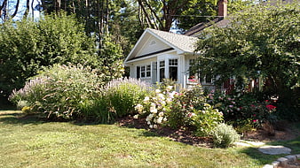 Charming White Cottage With Lush Flower Garden And Green Lawn
