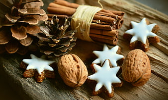 Christmas star cookies with walnuts, cinnamon, and pine cones on wood