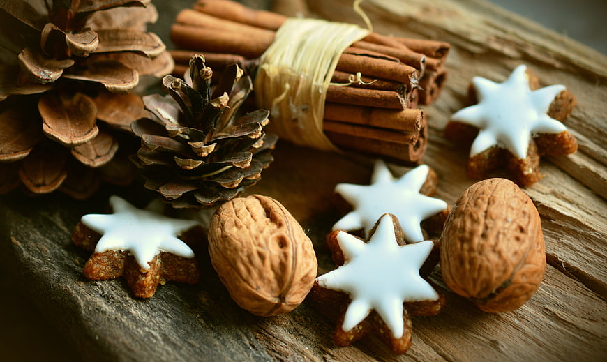 Christmas star cookies with walnuts, cinnamon, and pine cones on wood