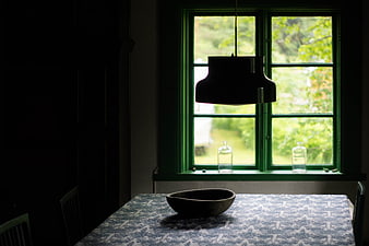 Dark interior dining table with green window and hanging lamp