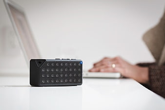Black Bluetooth Speaker on White Desk with Laptop