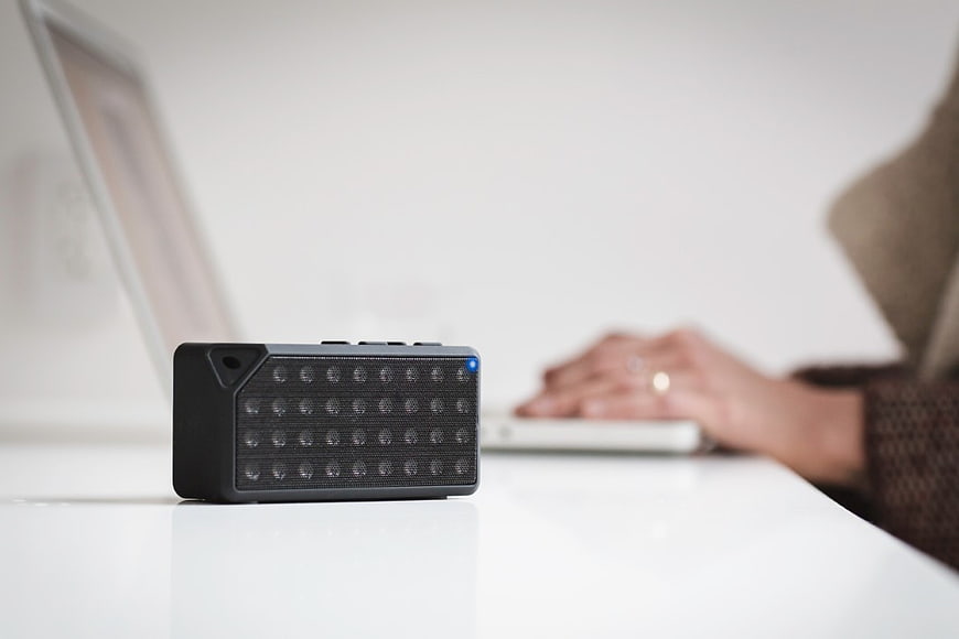 Black Bluetooth Speaker on White Desk with Laptop