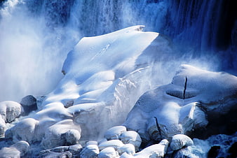 Frozen waterfall with snow-covered rocks and mist