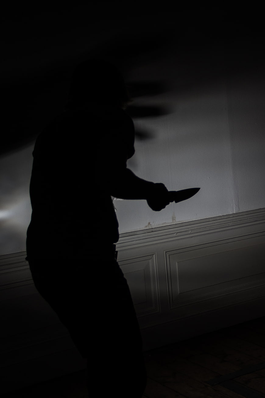 Silhouette of person holding knife in dark room