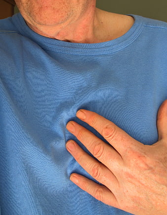 Man clutching chest in pain wearing blue t-shirt