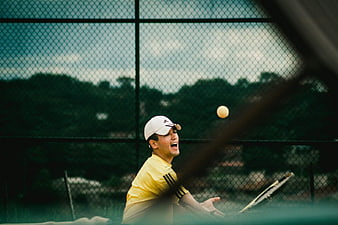 Tennis Player Serving Through Chain Link Fence