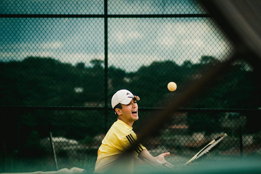 Tennis Player Serving Through Chain Link Fence