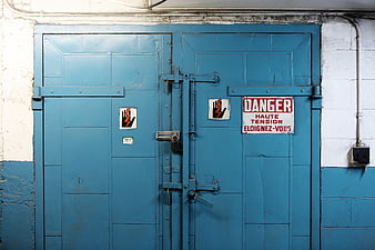 Blue industrial double doors with high voltage danger warning sign