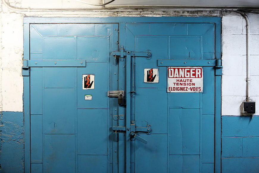 Blue industrial double doors with high voltage danger warning sign