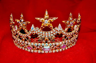 Sparkling gold tiara with rhinestones on red velvet background