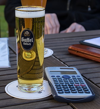 Gaffel Kölsch beer glass and calculator on wooden table