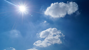 Bright Sun and Fluffy White Clouds in Blue Sky