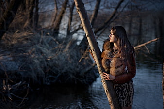 Woman in Fur Coat Standing by River in Winter Forest