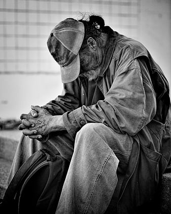 Black and white portrait of homeless man sitting on street