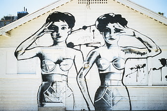Black and white graffiti mural of two women on house siding