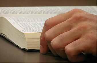 Close-up of a man's hand resting on an open book