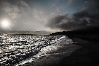 Dramatic moody seascape with waves crashing on dark beach