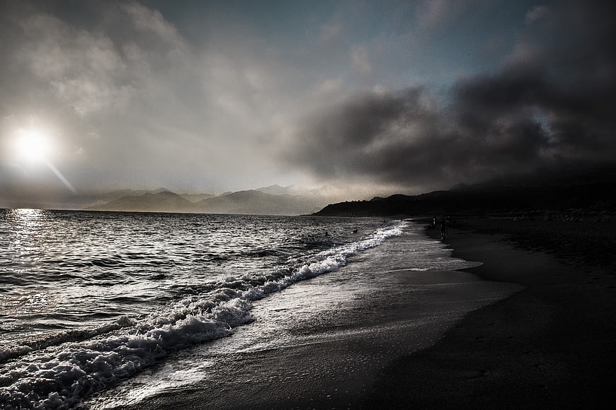 Dramatic moody seascape with waves crashing on dark beach