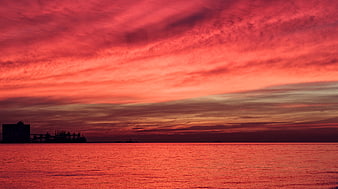 Dramatic Red Sunset Over Ocean with Silhouette of Port