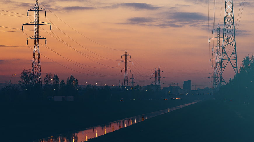 Silhouetted Power Lines Over River at Sunset
