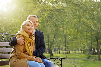 Happy Senior Couple Sitting on Park Bench in Spring