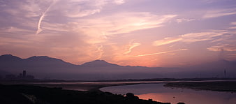 Panoramic sunset over river with mountains and city skyline