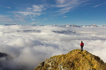 Hiker standing on mountain peak above sea of clouds