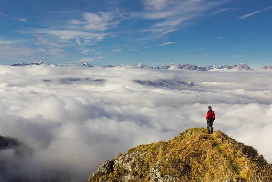 Hiker standing on mountain peak above sea of clouds
