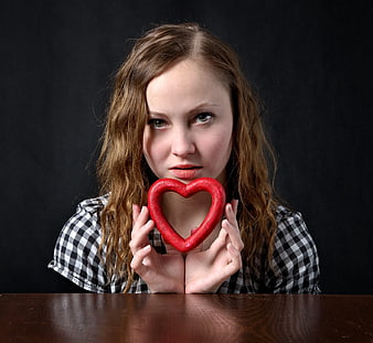 Woman holding red heart shape against black background