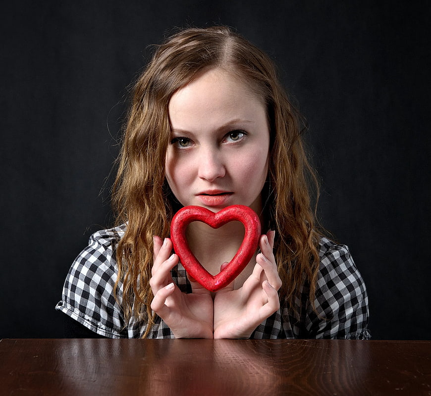 Woman holding red heart shape against black background