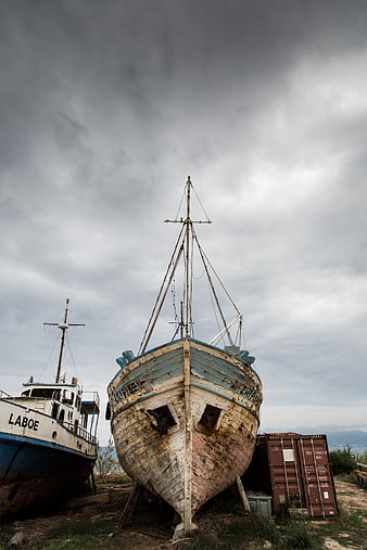 Weathered Fishing Boat on Shore Under Stormy Sky