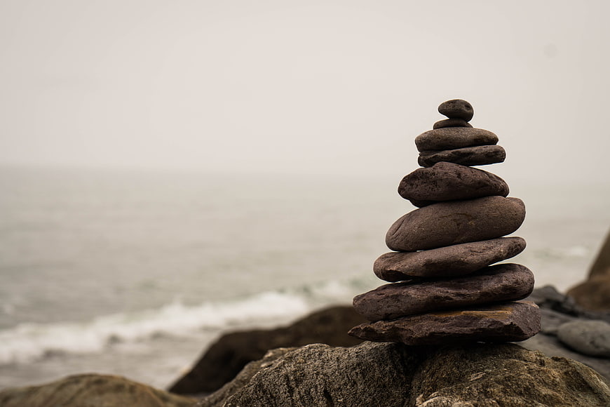 Stacked stones on rocky beach with ocean background