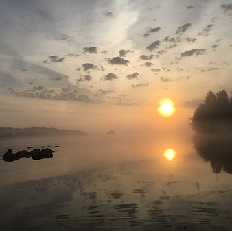Misty Sunrise Over Calm Lake with Silhouetted Trees