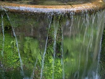Close-up of water flowing over mossy stone edge