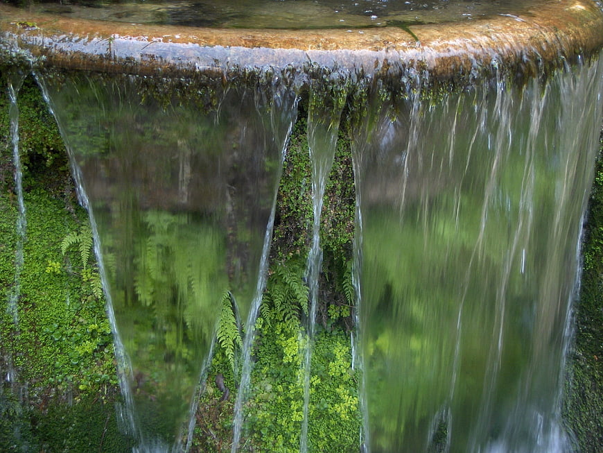 Close-up of water flowing over mossy stone edge