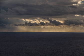 Dramatic sunset over the ocean with golden light rays through clouds