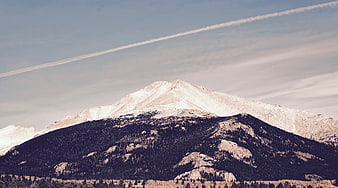 Snow-Capped Mountain Peak with Contrails in Blue Sky