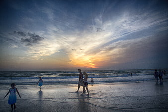 Family and Children Playing on Beach at Sunset