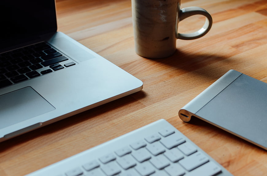 Modern Workspace with Laptop, Keyboard, and Coffee on Wooden Desk