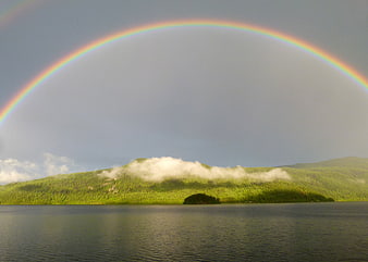 Vibrant Rainbow Arching Over Green Mountain Lake Landscape