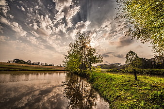 Dramatic Sun Rays Over River and Green Trees