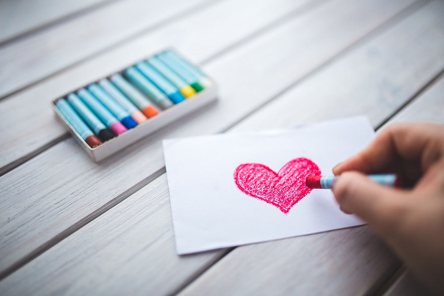 Hand drawing red heart with oil pastel on white paper