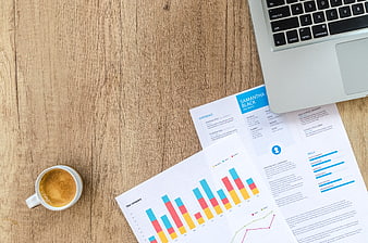 Flat lay of business documents, laptop, and coffee on wooden desk